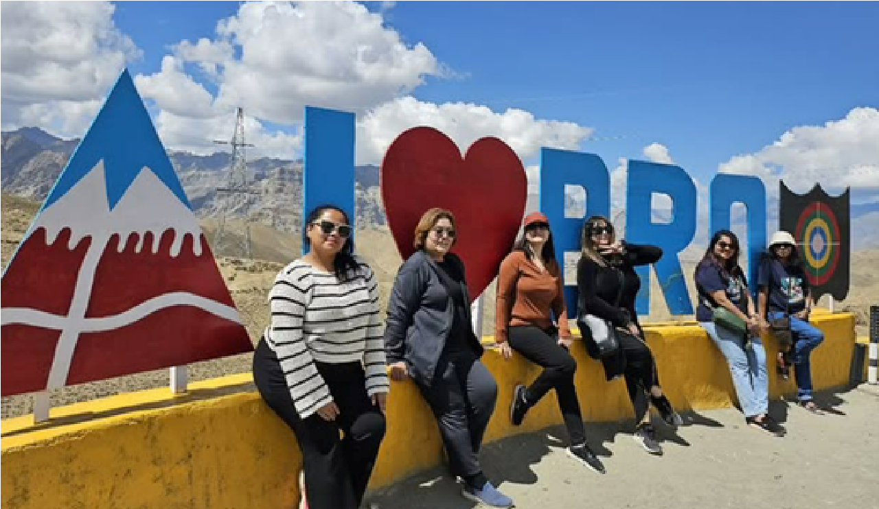 A group of women posing beside an I Love Pangong sign in the mountains on a Travel Bezzie trip